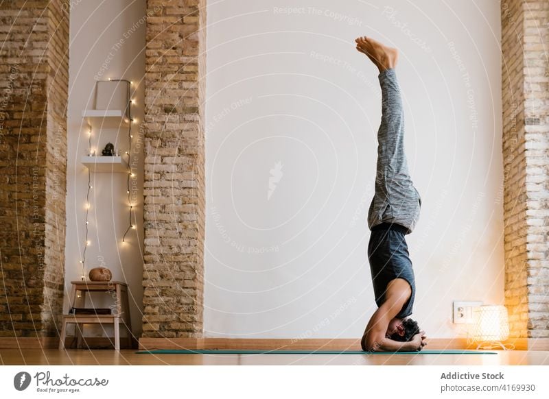 Anonymer Mann macht Kopfstand im Studio Yoga Atelier Lektion üben auf den Kopf gestellt Gleichgewicht gemütlich Gesundheit männlich Erwachsener Barfuß Zen Asana
