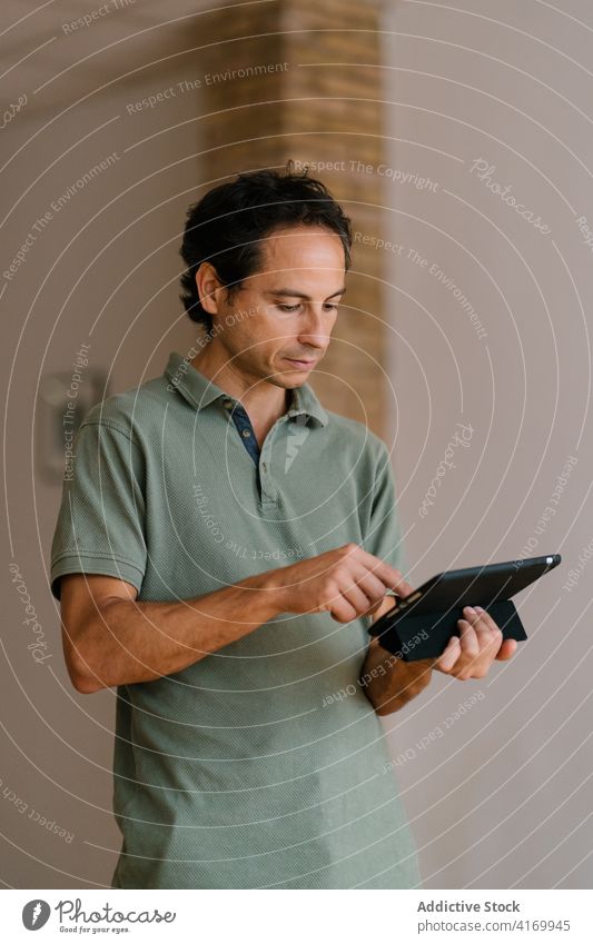 Erwachsener Mann mit modernem Tablet Tablette benutzend Daten Raum gemütlich lässig Anschluss männlich ethnisch Surfen online Internet Browsen Apparatur Gerät