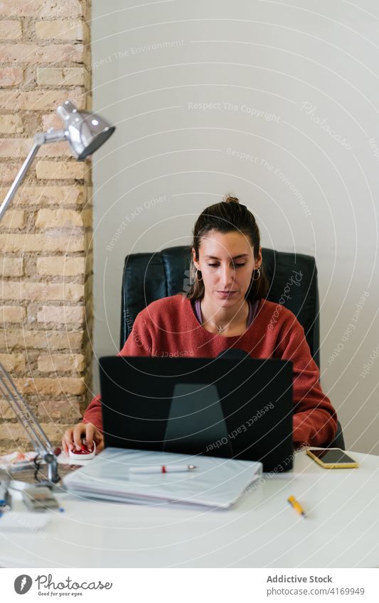 Frau benutzt Computer am Arbeitsplatz benutzend Lächeln Daten lässig jung Job Gerät Browsen Apparatur Laptop gemütlich online Arbeitsbereich Internet Büro