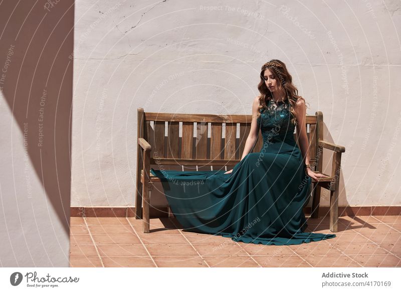 Anmutige Frau in langem Kleid auf einer Bank sitzend Smaragd elegant Stil charmant lange Haare Vorschein sich[Akk] entspannen maxi hölzern gewelltes Haar ruhen