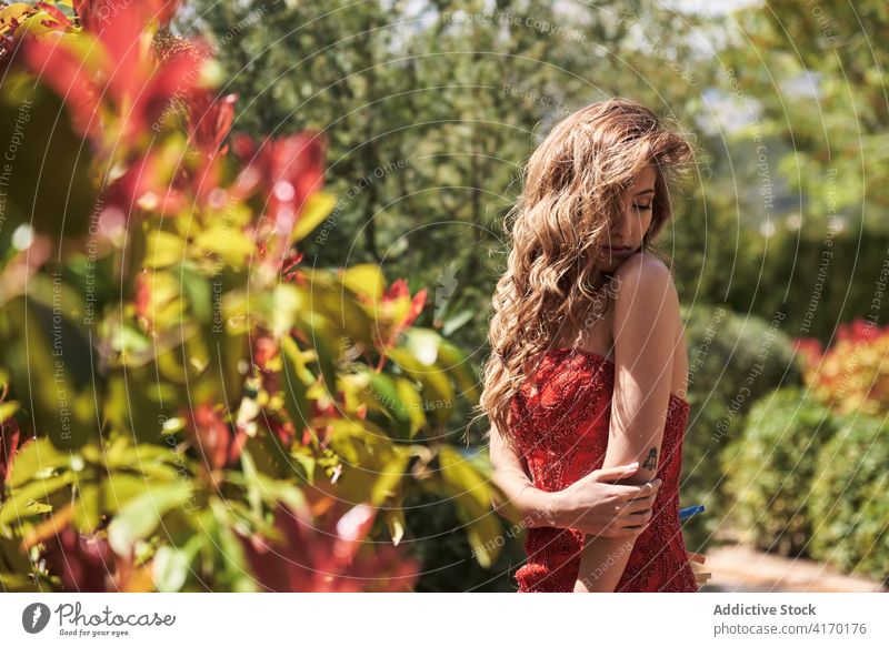 Anmutige Frau in rotem Kleid in üppigem Garten elegant verträumt Angebot üppig (Wuchs) Sommer jung Natur Stil lange Haare romantisch idyllisch ruhig genießen