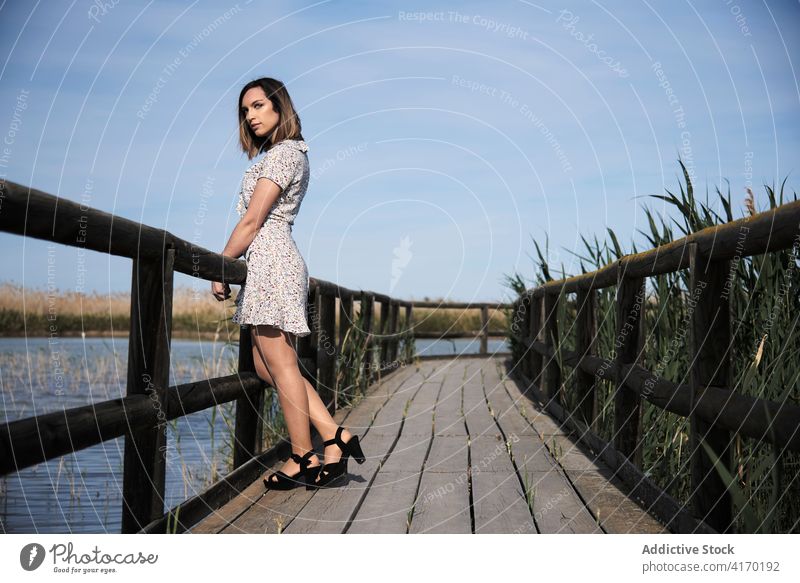 Frau stehend auf Holzbrücke über See Promenade Brücke hölzern Pier allein Sommer Natur Fluss Wasser ruhen Windstille Urlaub ruhig Landschaft Gelassenheit