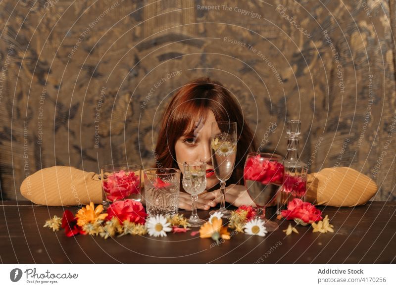 Frau und Komposition mit Blumen und Glaswaren Weinglas traurig einsam trinken besinnlich Rotschopf jung geblümt Stil Ingwer Dame verärgert unglücklich