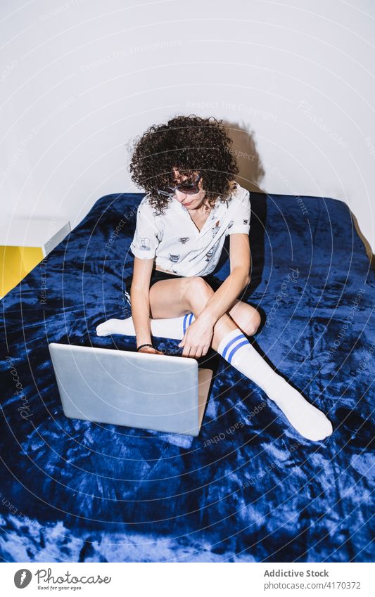 Junge Frau mit Laptop auf dem Bett sitzend benutzend Browsen soziale Netzwerke ruhen ernst Fokus Kälte konzentriert Netbook Sonnenbrille Gerät Apparatur online