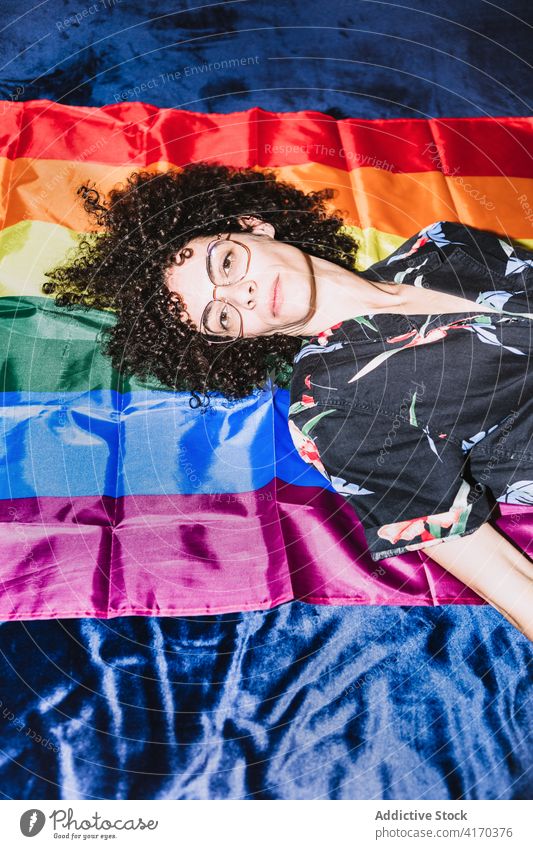Entspannte Frau liegend auf LGBT-Flagge auf dem Bett gleich Regenbogen Fahne Homosexualität Respekt Toleranz auf den Kopf gestellt rechts Gemeinschaft