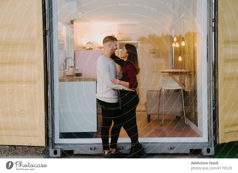 Ehepaar steht am Fenster eines Containerhauses Haus modern Paar kompakt Landschaft Gebäude Konstruktion verweilen kuscheln Zusammensein Liebe Partnerschaft Glas