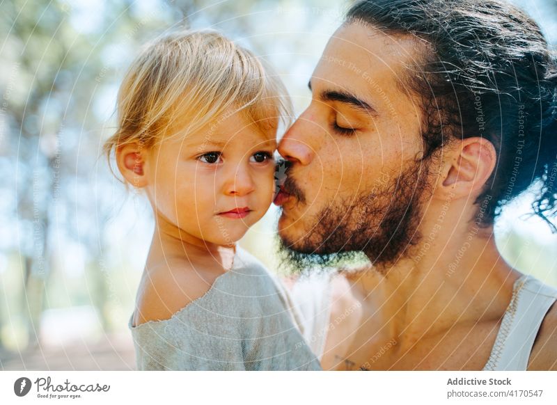 Glücklicher Vater küsst süßes Kind im Wald Kuss Wange Liebe niedlich Angebot Zusammensein Wochenende ethnisch rassenübergreifend vielfältig Elternschaft