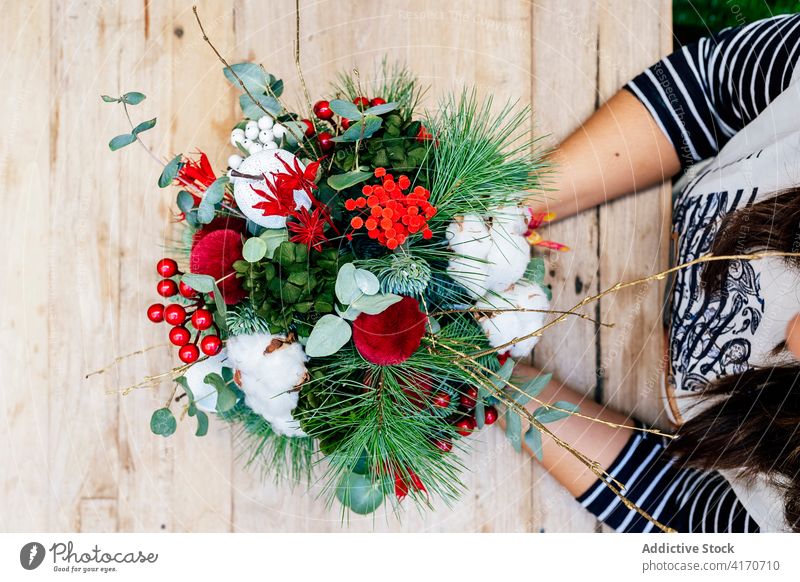 Anonyme Frau mit weihnachtlichem Blumenstrauß im Geschäft Feiertag Weihnachten Laden festlich Illumination Blumenhändler Blütezeit Straße Stubenschmuck Dezember