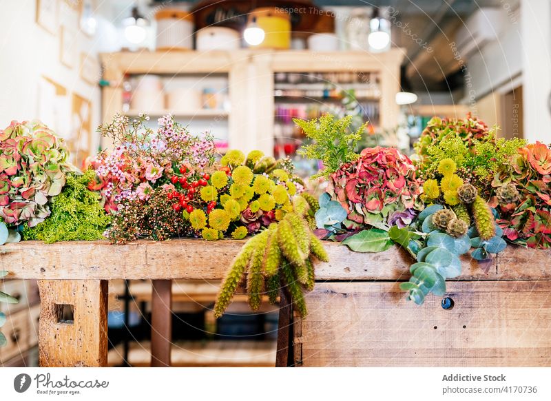 Holztisch in der Floristikwerkstatt voller Blumen für Gestecke Laden Blütezeit Blumenstrauß Feier Stubenschmuck Dekoration & Verzierung Werkstatt horizontal