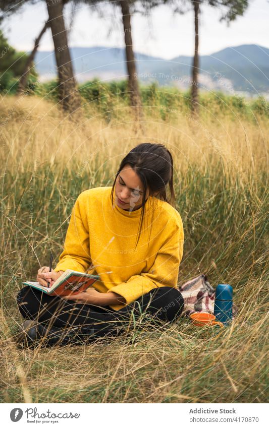Frau macht sich Notizen in einem Notizbuch in der Natur zur Kenntnis nehmen Tagebuch schreiben Notebook sich[Akk] entspannen nachdenklich reflektieren friedlich