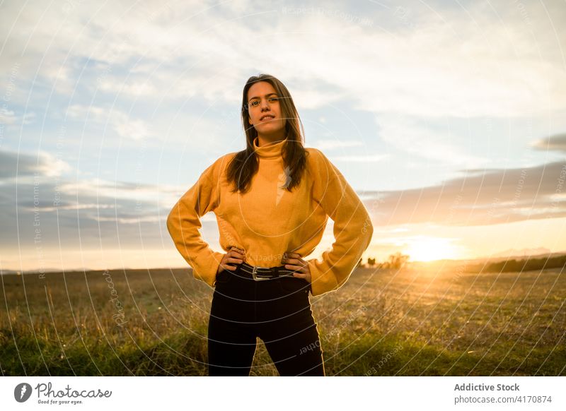 Glückliche Frau auf einem Feld bei Sonnenuntergang sorgenfrei Freiheit genießen Lächeln Landschaft Outfit lässig Wiese ländlich Gegend aktiv Herbst fallen