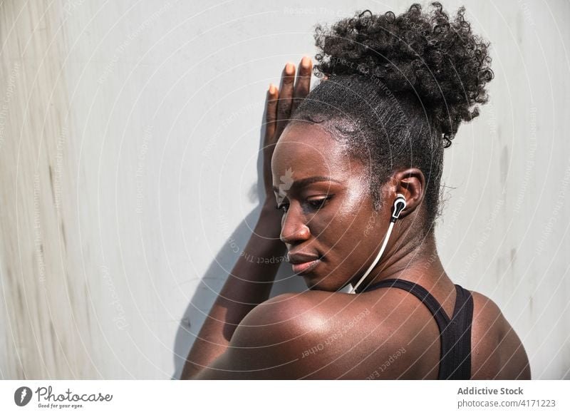 Seriöse ethnische Sportlerin beim Musikhören in der Stadt zuhören Kopfhörer Athlet Straße Großstadt Bestimmen Sie Training passen Frau schwarz Afroamerikaner