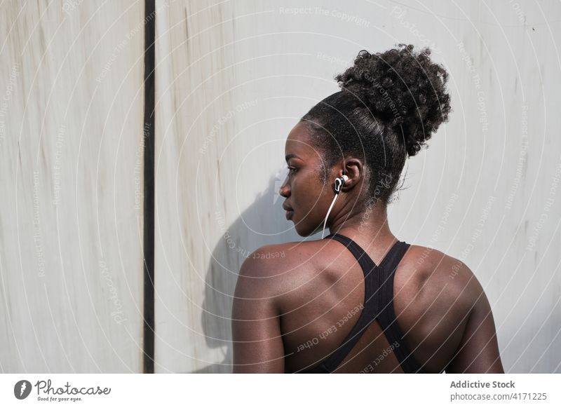 Seriöse ethnische Sportlerin beim Musikhören in der Stadt zuhören Kopfhörer Athlet Straße Großstadt Bestimmen Sie Training passen Frau schwarz Afroamerikaner