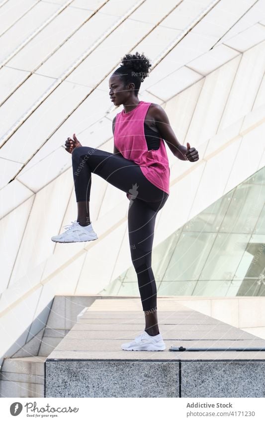 Ethnische Sportlerin beim Aufwärmen der Beine während des Trainings Großstadt Athlet aktiv Dehnung passen Frau ethnisch schwarz Afroamerikaner schlank