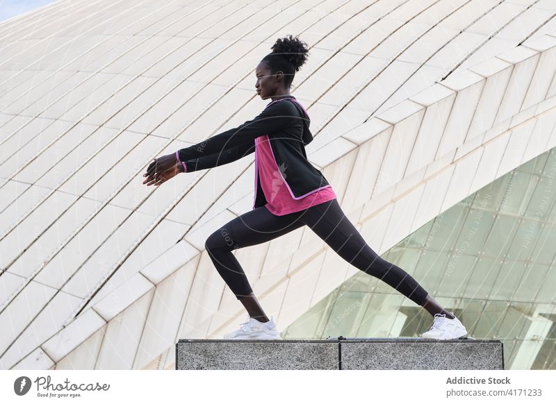 Schwarze Läuferin beim Aufwärmen auf der Straße Dehnung Bein Sportlerin Training Ausfallschritt Übung Athlet Frau schwarz ethnisch Afroamerikaner Großstadt