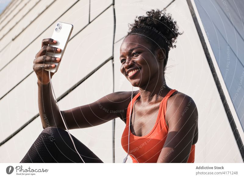 Ethnische Sportlerin, die mit Kopfhörern Musik hört Smartphone Selfie zuhören Athlet Straße Gesang heiter sich[Akk] entspannen Selbstportrait Frau unter