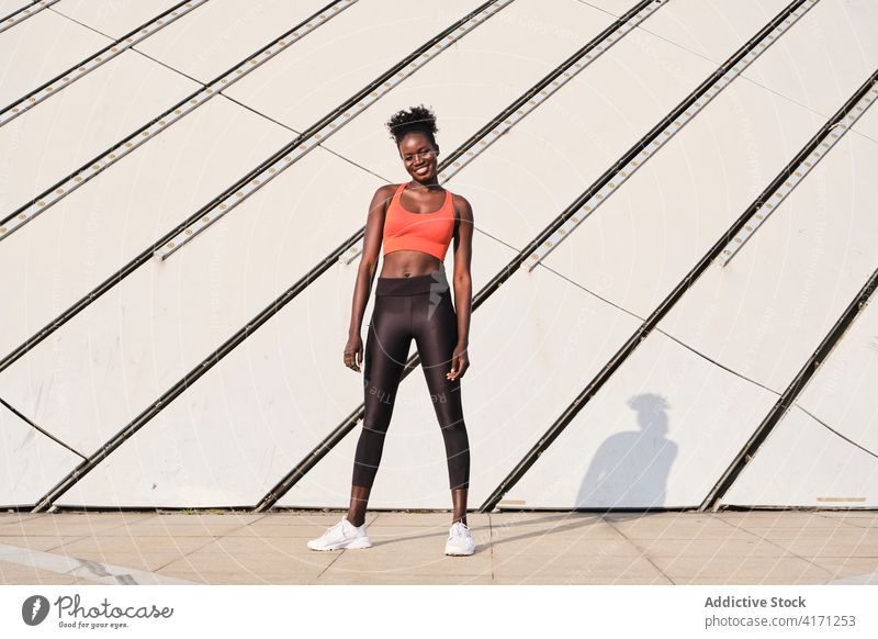 Schwarze Sportlerin auf der Straße an einem sonnigen Tag Athlet Großstadt Frau Lächeln schlank passen heiter ethnisch schwarz Afroamerikaner Sportbekleidung