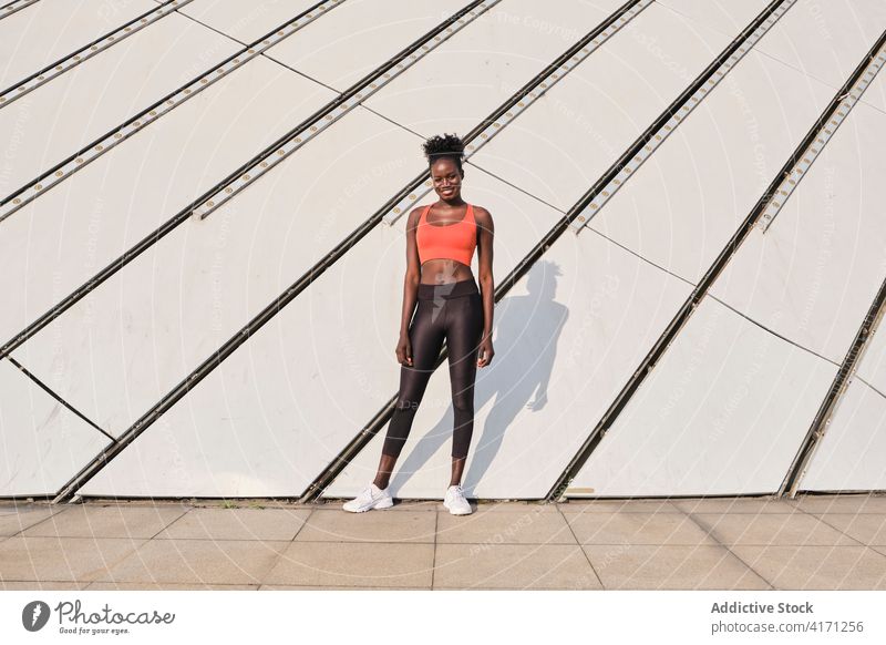 Schwarze Sportlerin auf der Straße an einem sonnigen Tag Athlet Großstadt Frau Lächeln schlank passen heiter ethnisch schwarz Afroamerikaner Sportbekleidung