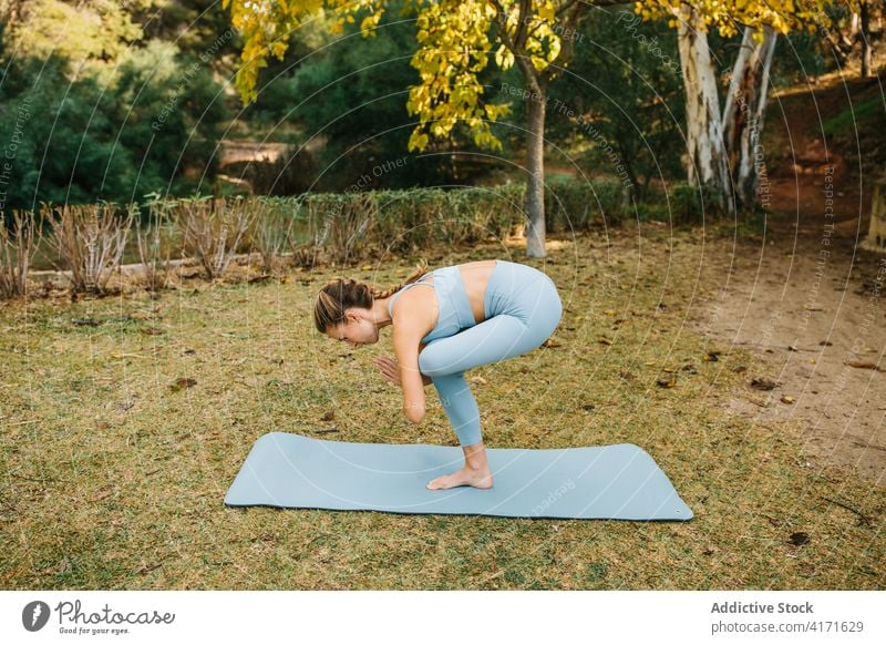 Flexible Frau, die eine einbeinige ausgleichende Yogahaltung im Park macht Einbeiniger Stuhl eka pada utkatasana Asana Pose üben Gleichgewicht stehen Wegbiegung