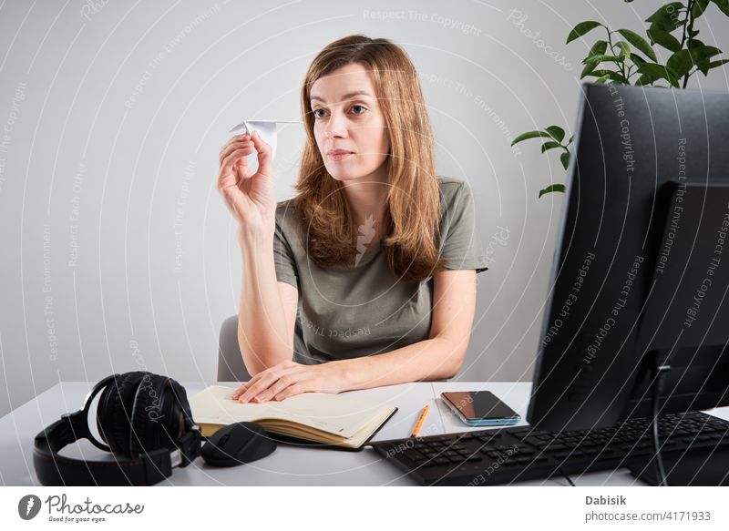 Frau hält Papierflugzeug bei der Arbeit im Büro zu Hause prokrastinieren freiberuflich online heimwärts LAZY Business Arbeitsbereich Computer Unternehmen
