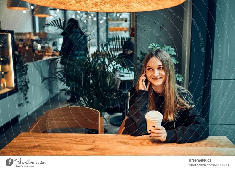 Junge Frau am Telefon im Café, mit einem angenehmen Telefongespräch, Beantwortung von Anrufen, Chatten per Handy mit Freund, während in einem Café sitzen und Kaffee trinken. Mädchen entspannt im Café