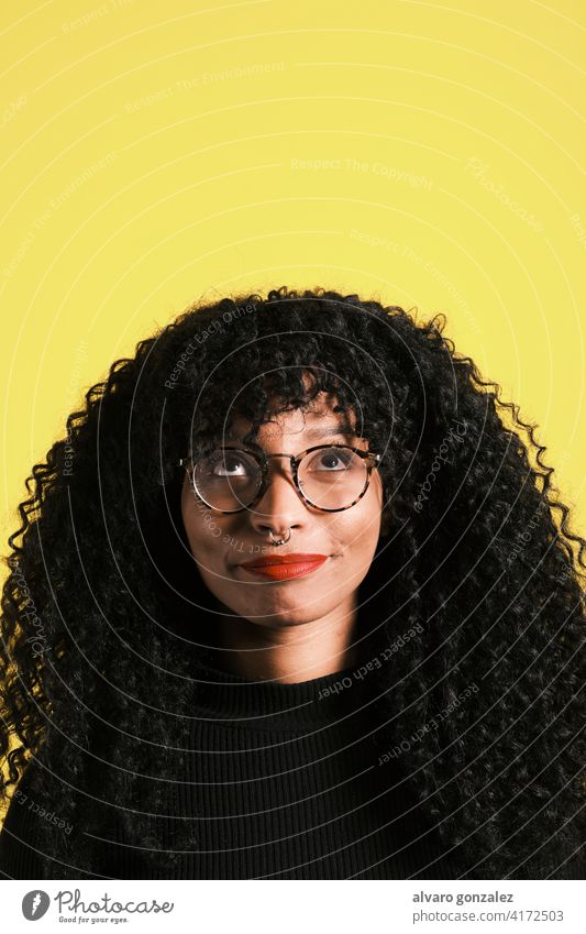 Junge afroamerikanische Frau schaut auf und hat eine Idee Afro-Look Amerikaner lockig Blick nach oben gelb Gedanken entspannt wirklich Zukunft Vorstellungskraft