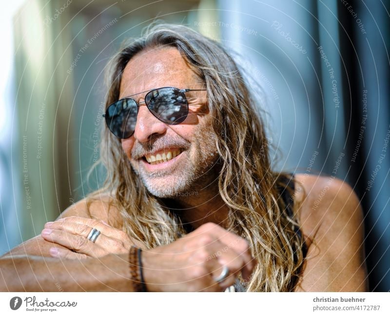 älterer hippie mit Sonnenbrille mann portrait 50 jahre sonne sommer lachen lange haare sonnenbrille gluecklich strahlend model Fröhlichkeit alternativ