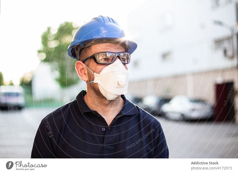 Arbeiter mit Schutzmaske und Brille steht auf der Straße Mechaniker Atemschutzgerät Mundschutz behüten professionell Handschuh Mann Beruf männlich Erwachsener