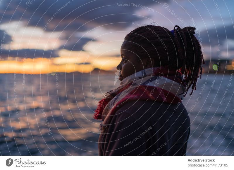Schwarze Frau genießt den Sonnenuntergang über dem Meer MEER genießen bewundern Abend Meereslandschaft ruhig warme Kleidung kalt ethnisch schwarz Afroamerikaner