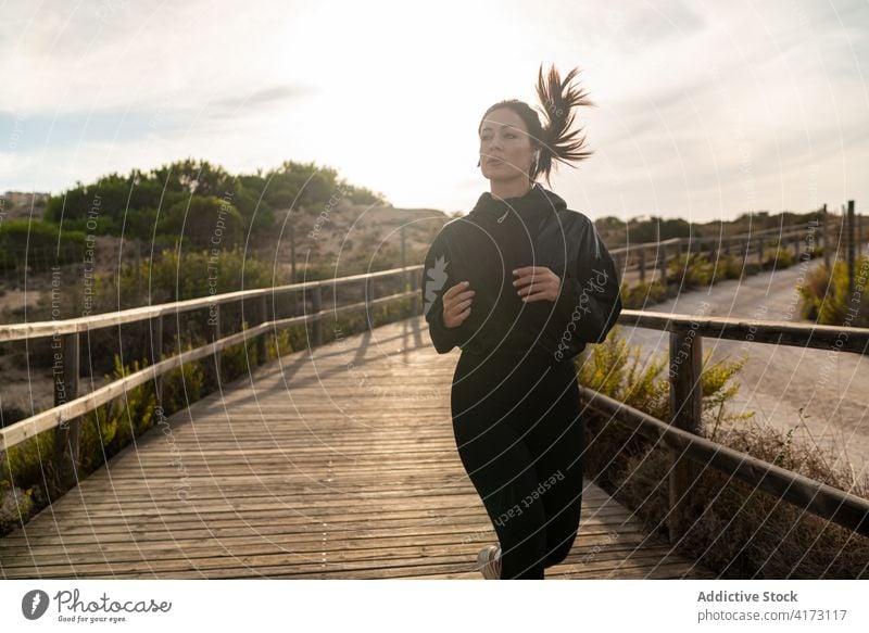 Fitte Frau läuft auf hölzernem Fußweg laufen Fitness sportlich Training Übung aktiv passen Weg Natur jung Lifestyle Wellness Aktivität Vitalität Energie schlank