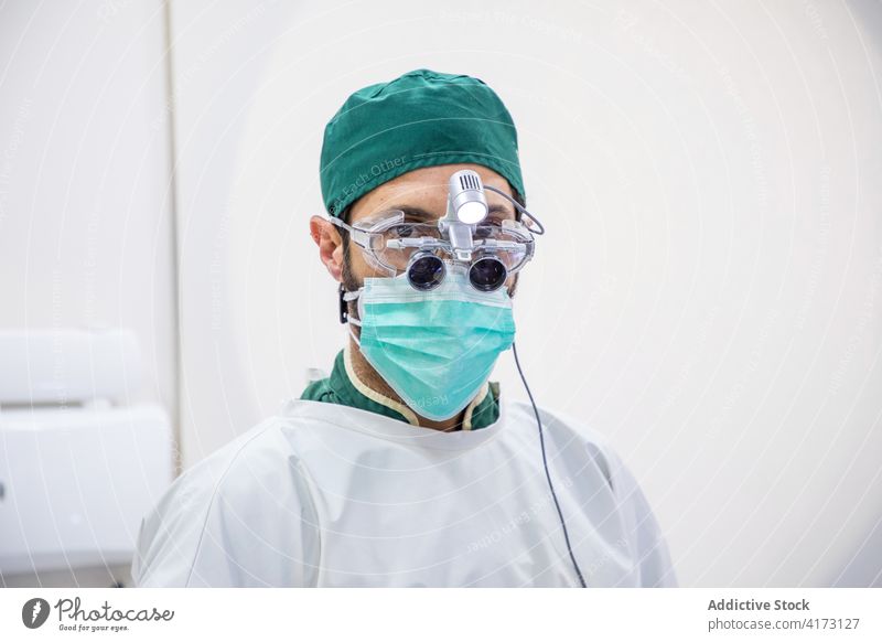 Männlicher Zahnarzt mit medizinischem Fernglas in der Klinik Mann dental Brille Zahnmedizin Raum Mundschutz männlich Arzt professionell Leckerbissen