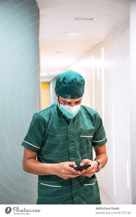 Männlicher Arzt mit Smartphone in einer Zahnklinik dental Klinik Zahnarzt Mann benutzend Arbeit männlich Mundschutz Uniform Medizin modern Funktelefon Gerät