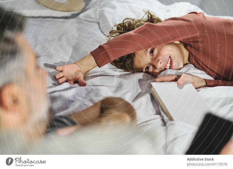 Freudiger Sohn spielt mit Vater im Schlafzimmer Lachen spielen Kribbeln Spaß haben Wochenende Zusammensein Vaterschaft Kindheit Lügen Bett Junge heiter Liebe