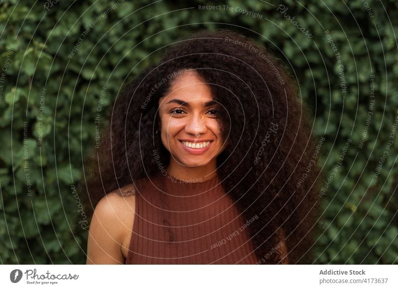 Glückliche ethnische Frau im grünen Garten charmant Lächeln natürlich Schönheit offen krause Haare Afro-Look Frisur Park schwarz Afroamerikaner jung heiter