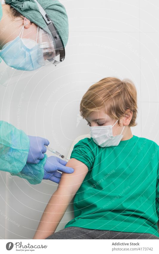 Arzt gibt Injektion für Kind in Maske im Krankenhaus Impfstoff Coronavirus Einspritzung Spritze verhindern Bund 19 steril Gesundheitswesen medizinisch COVID