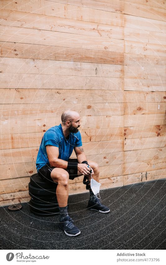 Sportler entspannt sich beim Training im Fitnessstudio Pause Mann sich[Akk] entspannen müde Müdigkeit Mundschutz männlich neue Normale Coronavirus Gesundheit