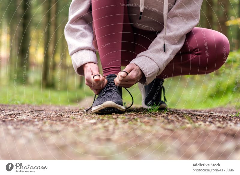 Anonyme sportliche Frau beim Schnürsenkelbinden im Wald Krawatte Schuhbänder Sportlerin Turnschuh Training Wälder Schuhe Athlet passen Sportkleidung Fitness