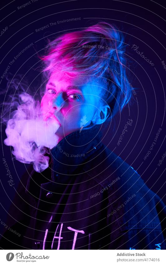Ausdrucksstarke Frau beim Rauchen im dunklen Studio Raps e Zigarette neonfarbig Atelier Licht dunkel Verdunstung cool Stil Nikotin Raucherin Habitus
