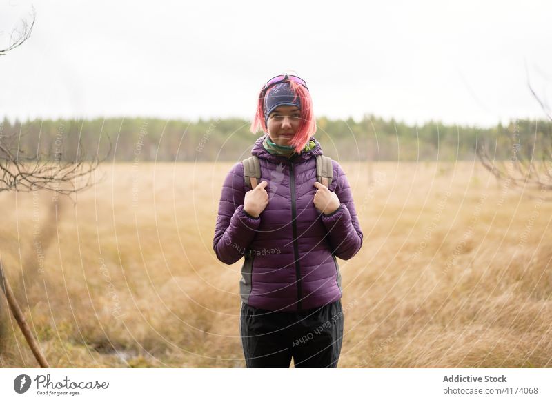 Lächelnde weibliche Reisende auf einem trockenen Feld an einem kalten Tag trocknen Frau reisen getrocknet erkunden Abenteuer Backpacker rosa Haare sestroretsk