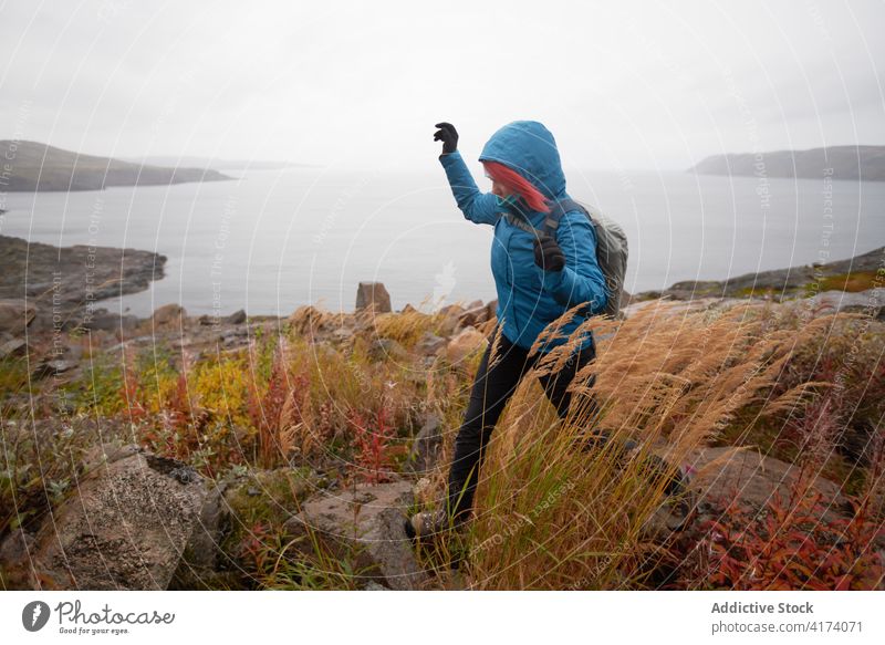 Reisende Frau beim Wandern im Hochland in der Nähe des Meeres Wanderung Reisender Trekking Herbst felsig Gelände Entdecker Rucksack kalt Wetter warme Kleidung