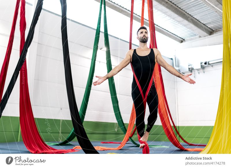 Bärtige Tänzerin balanciert auf Luftseiden Mann Tanzen Antenne Seide Gleichgewicht Atelier Probe gymnastisch akrobatisch hängen männlich ohne Hemd Bändchen