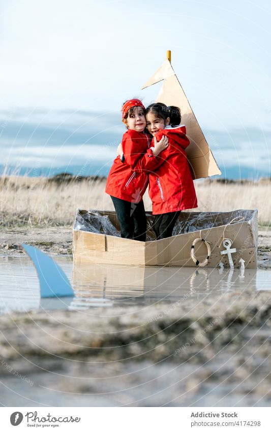 Verspielte Mädchen stehen im Kartonboot und haben Spaß Boot erschrecken Haifisch Vorstellungskraft Spaß haben Schachtel Kind spielen Zusammensein Inspiration