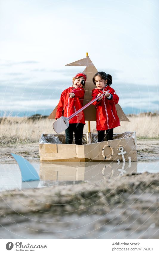 Aufgeregte Mädchen spielen in Karton Boot auf dem Lande Spaß haben Schachtel Kind Zusammensein Inspiration Paddel Spiel kreativ Vorstellungskraft handgefertigt