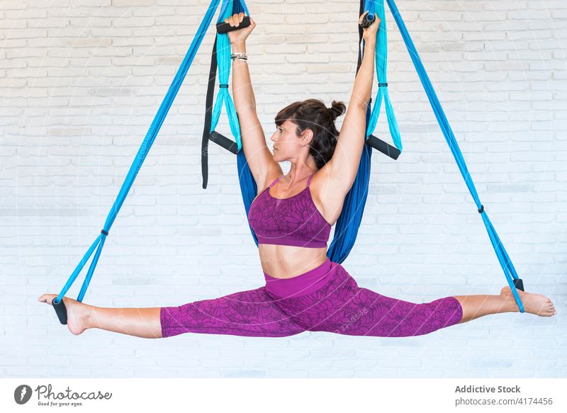 Fitte Frau macht Luftspagat an Bändern Spagat Antenne Seide Pilates Fitnessstudio üben Fliege Gleichgewicht Dehnung Erwachsener beweglich Yoga Backsteinwand