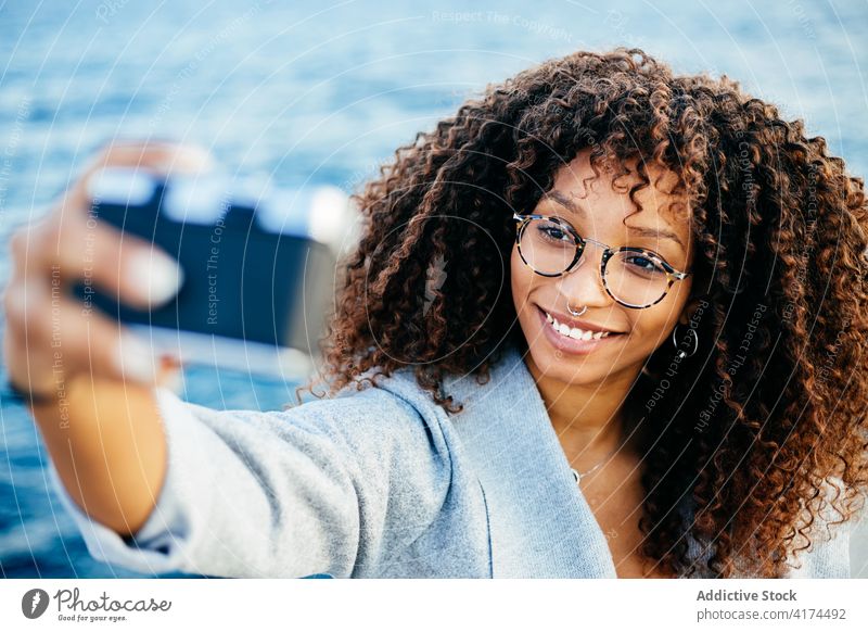Glückliche afroamerikanische Frau nimmt Selfie in der Nähe von Meer MEER Lächeln Wochenende Fotoapparat Wasser Ufer jung ethnisch schwarz Afroamerikaner