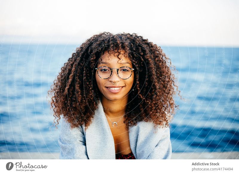 Fröhliche schwarze Frau an der Uferböschung stehend Stauanlage MEER Lächeln Stil Wochenende Glück Outfit ruhen jung Kai heiter ethnisch Afroamerikaner Wasser