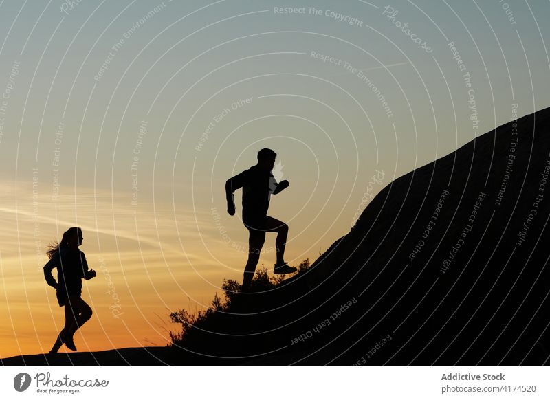 Athleten laufen in den Bergen bei Sonnenuntergang Silhouette Läufer Berge u. Gebirge Training felsig Gelände Sommer Sportlerin Hochland Abenddämmerung Dämmerung