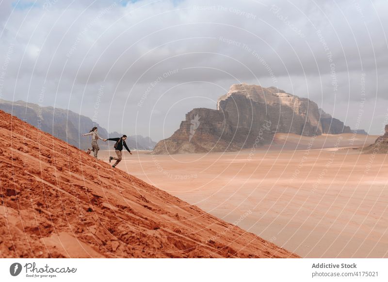 Sorglos reisendes Paar, das in der Wüste einen Hügel hinunterläuft sorgenfrei wüst Sand laufen Freiheit genießen Sandstein Tal Wadi Rum Jordanien Natur