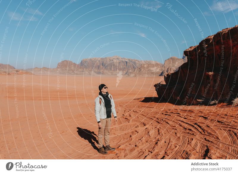 Reisender in der Wüste mit Bergen im Urlaub stehend wüst Sandstein Tal erkunden Tourist trocken trocknen Natur Fernweh Wadi Rum Jordanien Oberbekleidung