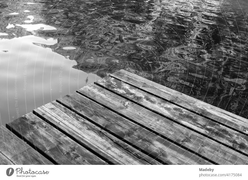 Alter Holzsteg für Badegäste im Sommer am Mittersee in Füssen im Ostallgäu im Freistaat Bayern, fotografiert in klassischem Schwarzweiß Steg Badesteg Rustikal
